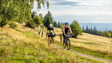 Two cyclists riding on a path through an autumn landscape
