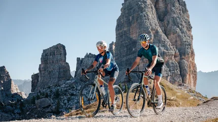 Zwei Radfahrer fahren auf einem Bergweg mit Felsen im Hintergrund