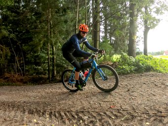 Radfahrer mit orange Helm fährt auf Waldweg