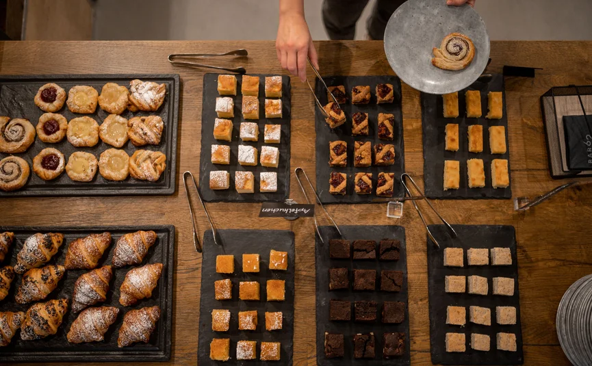 Assorted small pastries and croissants served on a wooden table