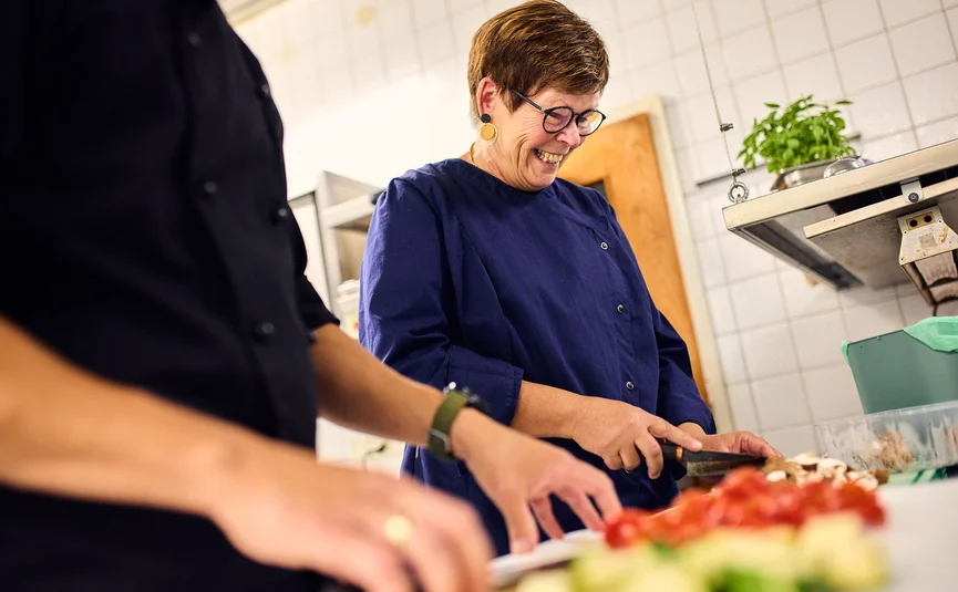 Woman chopping vegetables in kitchen smiling