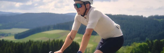Gravelbike Urlaub in Baden-Württemberg © David Lemanski Radfahrer in Sportkleidung fährt auf Landstraße mit grüner Landschaft im Hintergrund