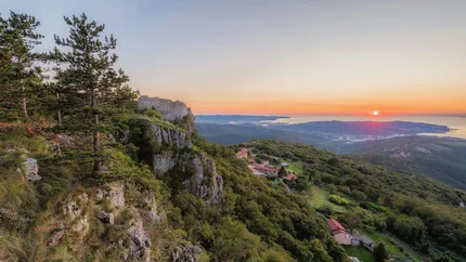 Sunset over hills with trees and houses on the slope