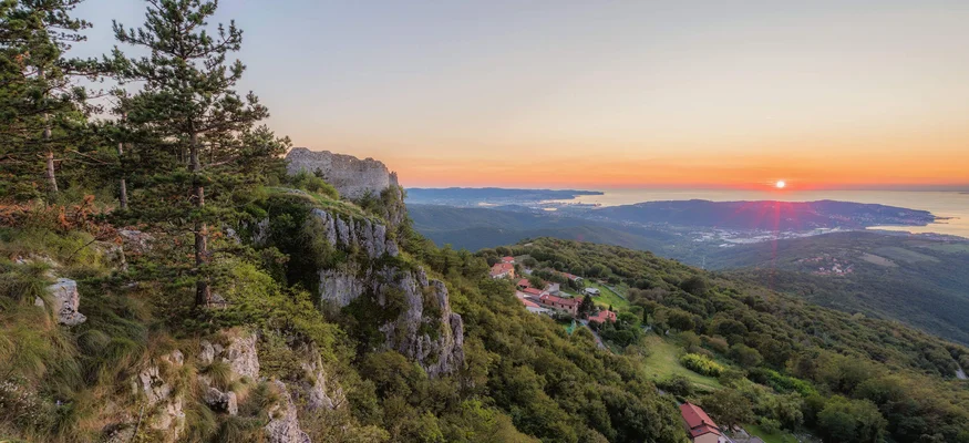 Sunset over hills with trees and houses on the slope