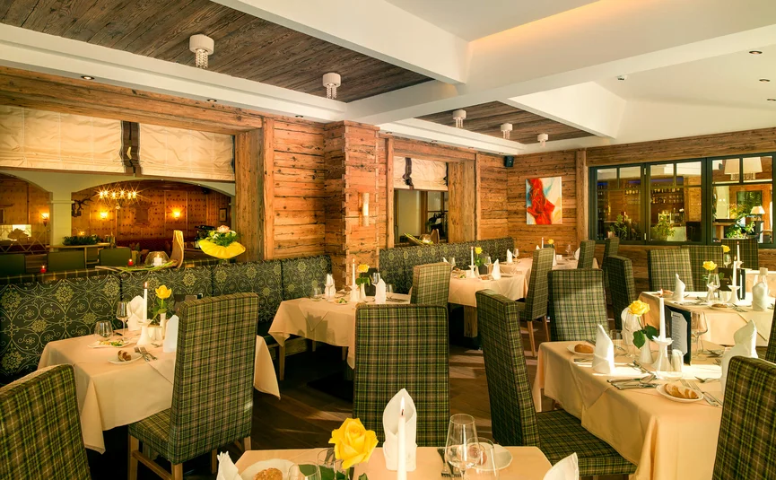Aktivhotel Alpendorf **** © Atelier Oczlon Elegantes Restaurant mit holzverkleideten Wänden und gedeckten Tischen