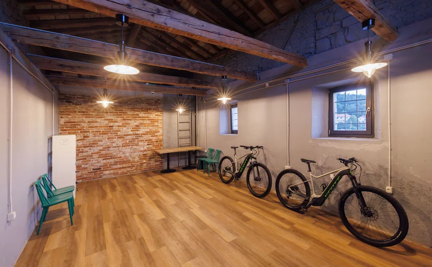 Spacious room with wooden floors, two bicycles, and exposed wooden ceiling beams