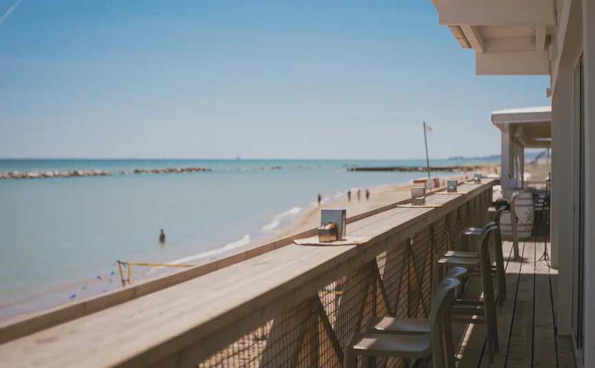 View of beach and sea from balcony with chairs at beach bar