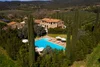 Stone house with pool surrounded by trees in a green hilly landscape