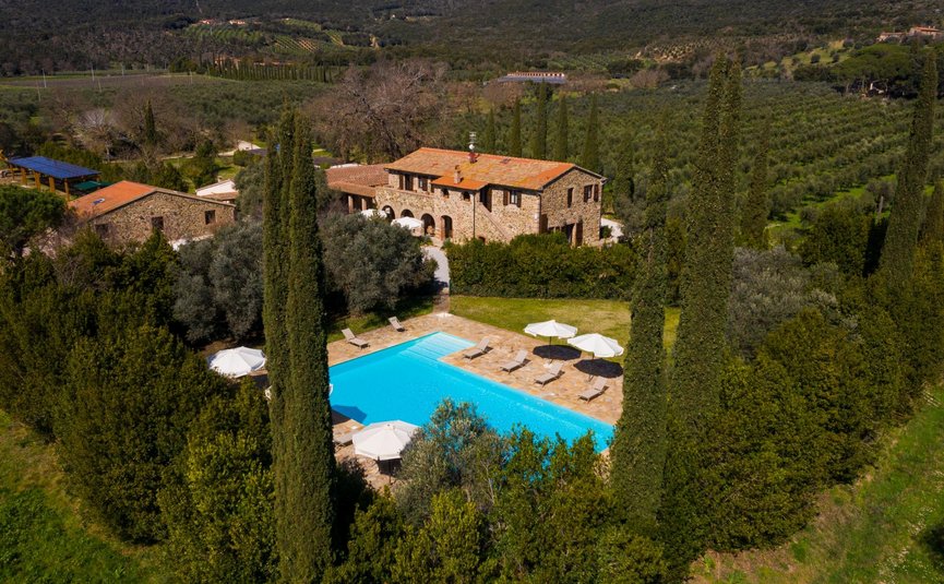 Steinhaus mit Pool umgeben von Bäumen in einer grünen Hügellandschaft