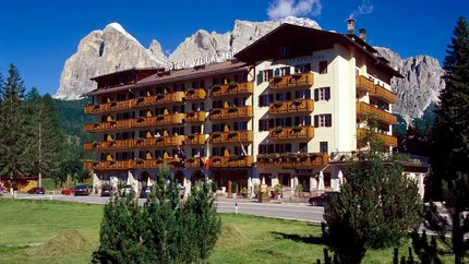 Hotel Villa Argentina vor Bergen und grünem Rasen bei klarem Himmel