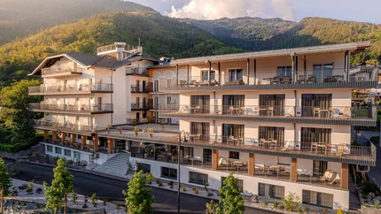 Modernes Hotelgebäude vor bewaldeten Bergen im Sonnenlicht