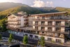 Modern hotel building with balconies in sunlight and forested mountains