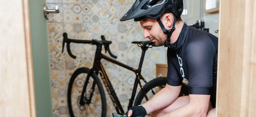 Hotel zur Post ***S © Martin Hoffmann Cyclist wearing helmet checks smartphone in a room with a bike