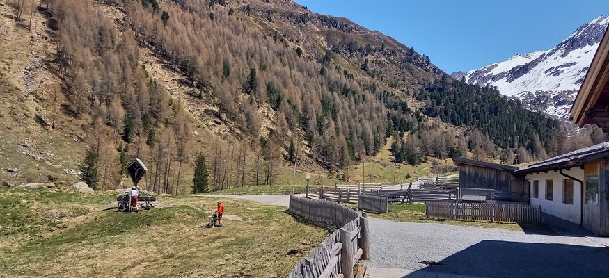 Berglandschaft mit Fahrradfahrern und einem Haus im Tal