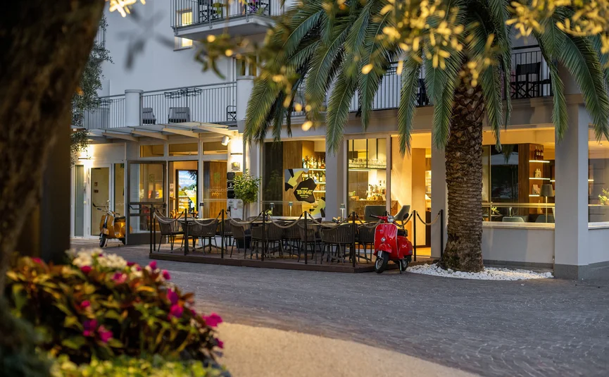 Lit outdoor seating area of restaurant with red and orange scooters
