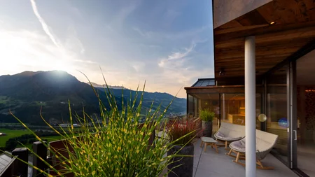 Balkon mit Pflanzen und Blick auf Berge bei Sonnenuntergang