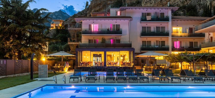 Beleuchteter Pool und Hotelgebäude bei Sonnenuntergang vor Felsen