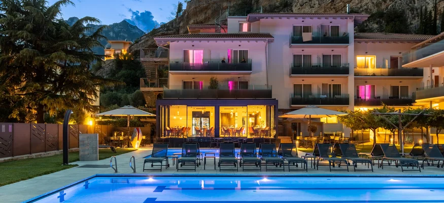 Beleuchteter Pool und Hotelgebäude bei Sonnenuntergang vor Felsen