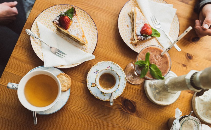 Tee, Espresso, Smoothie und Erdbeerkuchen auf Holztisch serviert