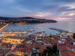Evening view of harbor and town with illuminated buildings by the water