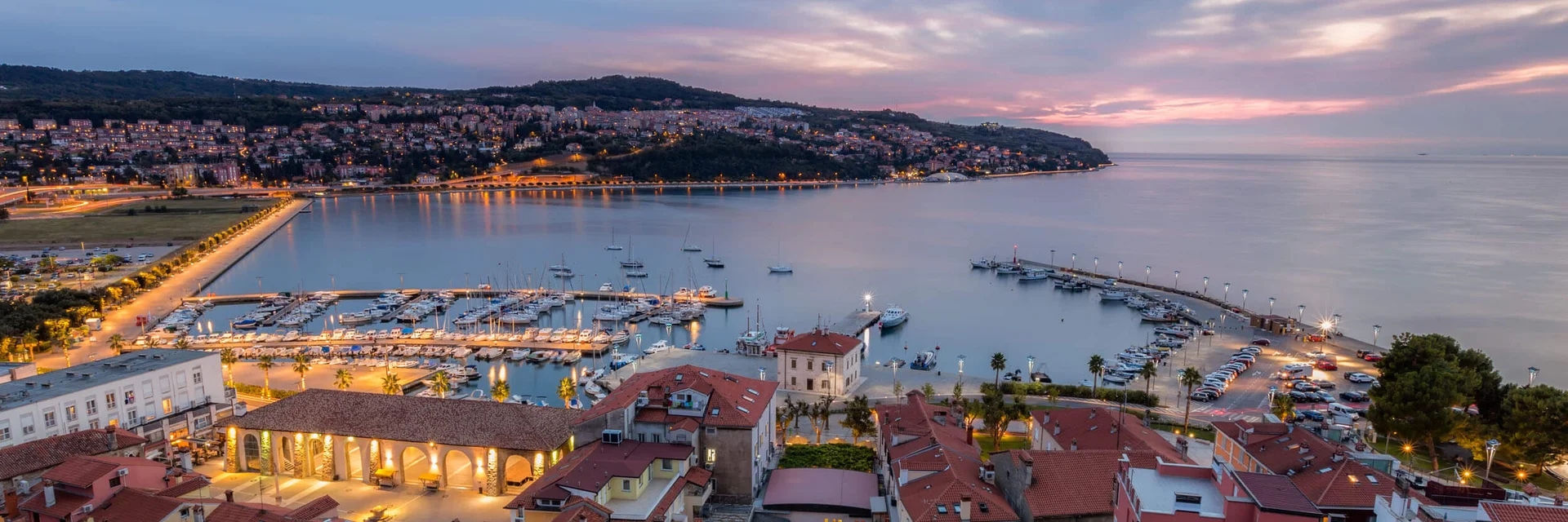 Evening view of harbor and town with illuminated buildings by the water