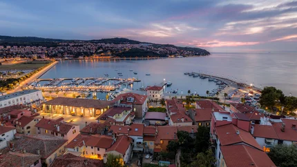 Evening view of harbor and town with illuminated buildings by the water