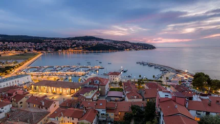 Evening view of harbor and town with illuminated buildings by the water