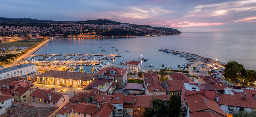 Abendlicher Blick auf Hafen und Stadt mit beleuchteten Gebäuden am Wasser