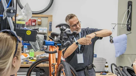 Das war das Ride ’n Gravel Testival 2026! © Sport Conrad-Leon Hoesch Mann repariert Fahrrad in Werkstatt, orange Fahrrad im Vordergrund