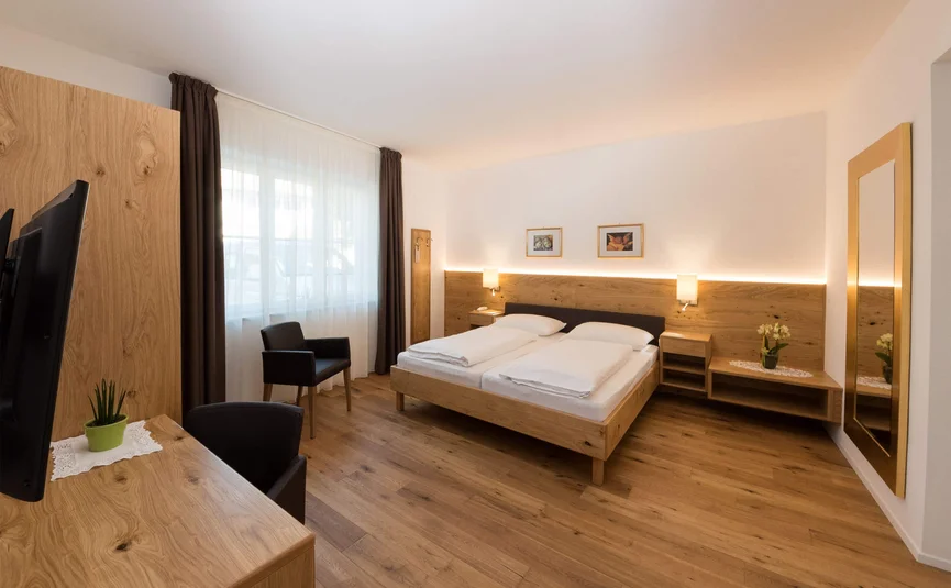 Helles Hotelzimmer mit Doppelbett, Holzfußboden und Fernseher