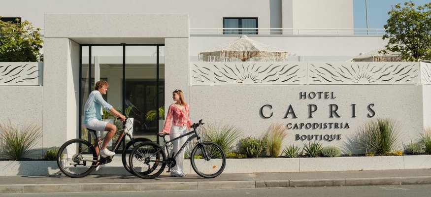 Zwei Personen mit Fahrrädern vor dem Eingangsbereich des Hotel Capris Boutique