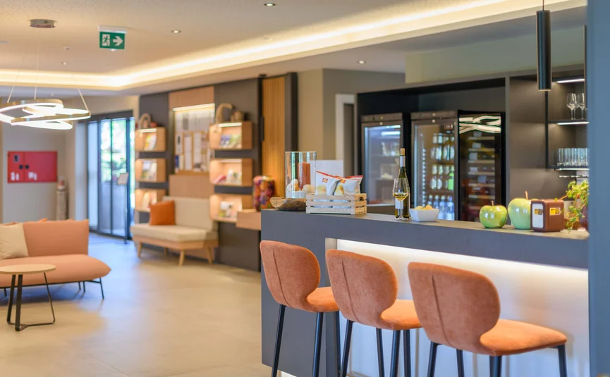 Modern hotel bar with orange bar stools and sofas in the background