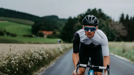 Man cycling on a country road under cloudy sky