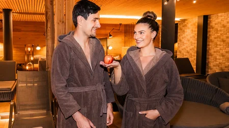 Paar in Bademänteln im Spa, Frau hält roten Apfel