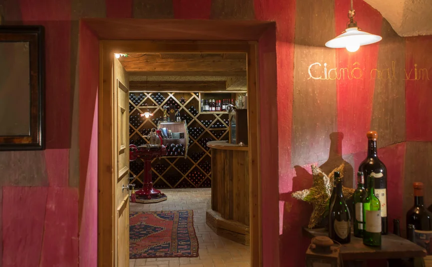 Weinkeller mit Holztür, Weinregalen und Flaschen auf Tisch