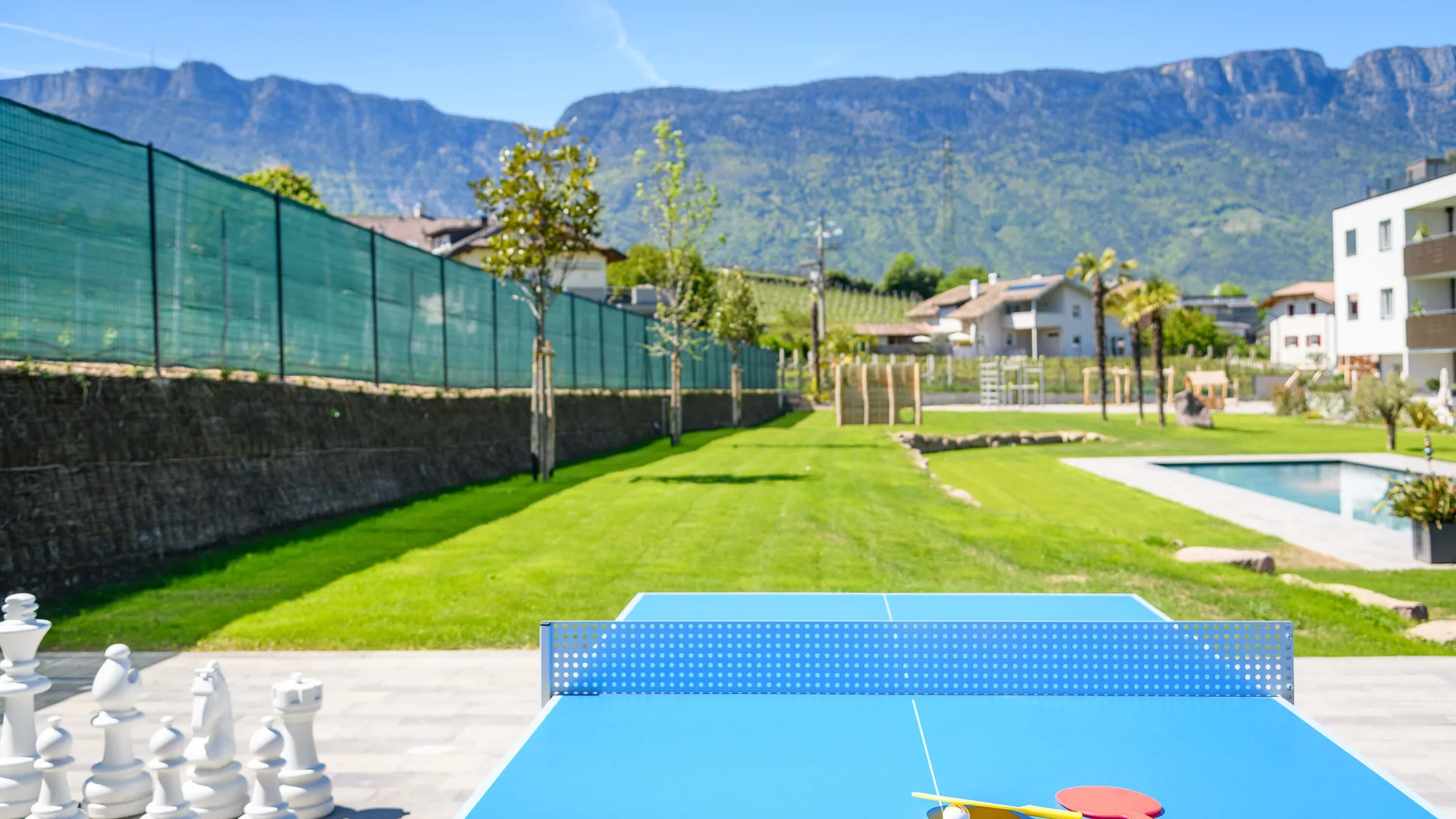Tischtennisplatte mit Schlägern vor großem Schachspiel und Bergblick