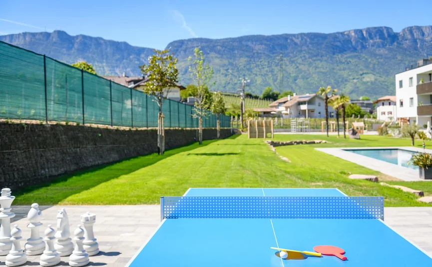 Ping pong table with paddles next to giant chess game and mountain view