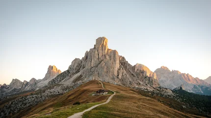 Trail leading to mountain hut below rocky peak at sunset