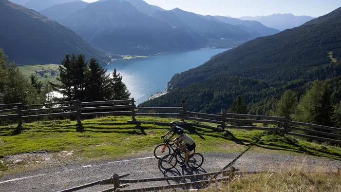 Ein Gravel-Wochenende in Nauders-Reschensee © Heiko Mandl Zwei Radfahrer auf Bergweg mit Blick auf See und Alpenberge