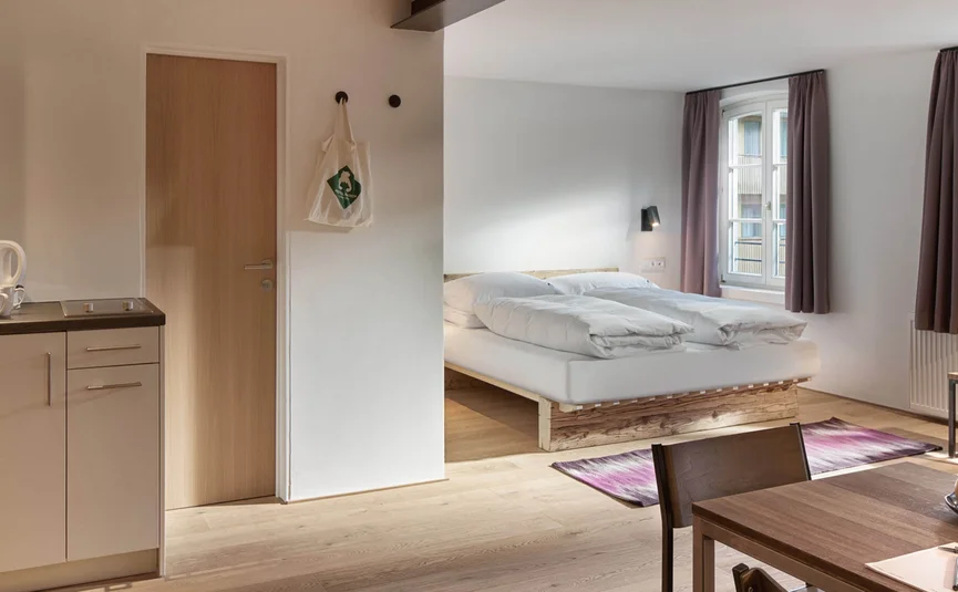 Modernes Apartment mit Küchenzeile, Esstisch und Doppelbett bei Tageslicht