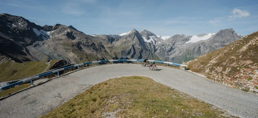 Gravelbike Urlaub im SalzburgerLand © Salzburger Land Tourismus - Roastmedia Zwei Radfahrer fahren auf einem bergigen, gepflasterten Serpentinenweg im Hochgebirge