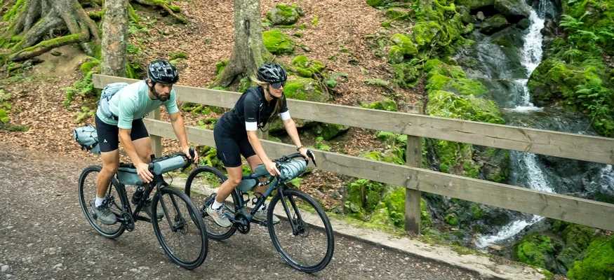 Posthorn Hotel-Restaurant © Hochschwarzwald Tourismus GmbH - Baschi Bender Zwei Radfahrer überqueren eine Brücke an einem Bach im grünen Wald
