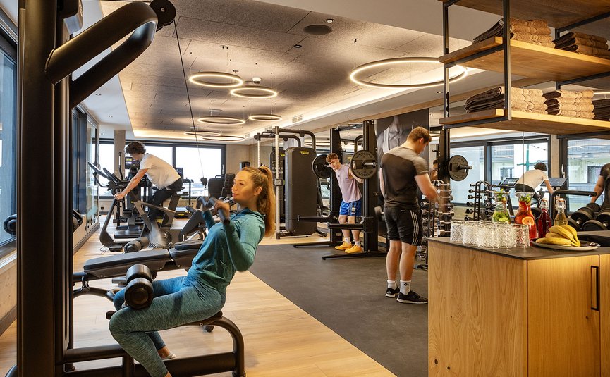 Menschen trainieren in einem modernen Fitnessstudio mit Geräten und Getränkebereich