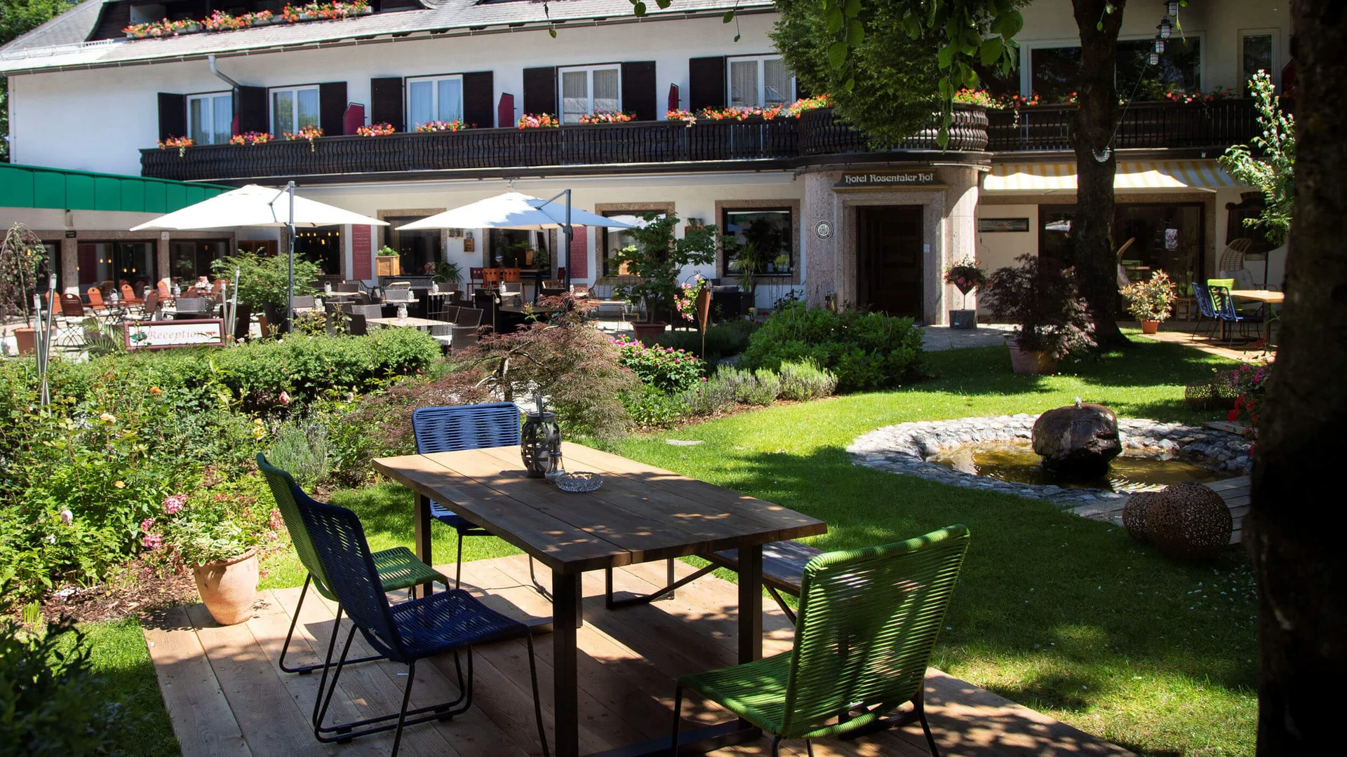 Garden terrace with table, chairs, and fountain in front of a hotel