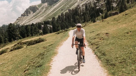 Gravelbiken ist eine Welt zwischendrin. © John Braynard Fahrradfahrer auf Bergweg mit steilen Felsen im Hintergrund