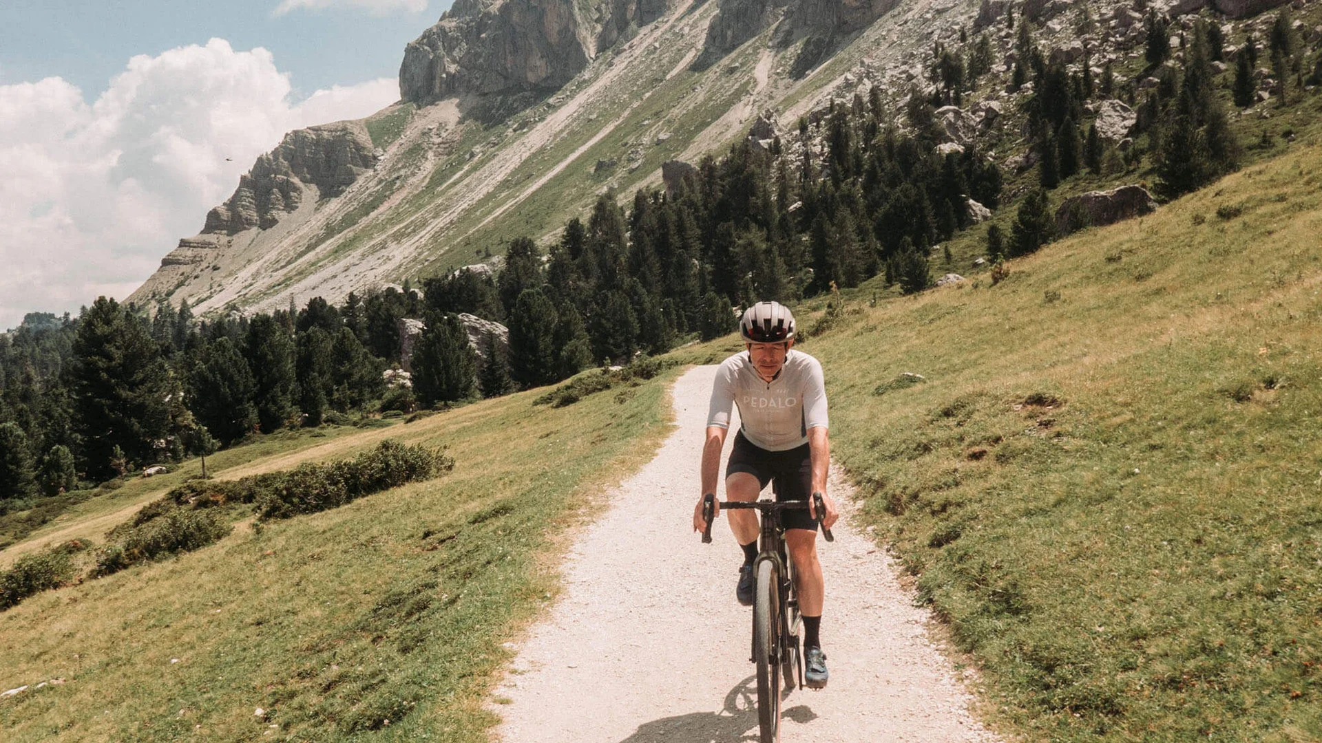 Fahrradfahrer auf Bergweg mit steilen Felsen im Hintergrund