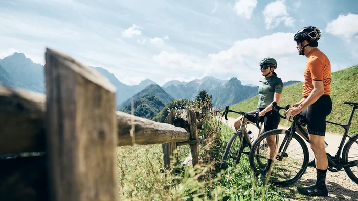 Two cyclists pause and look at mountain landscape