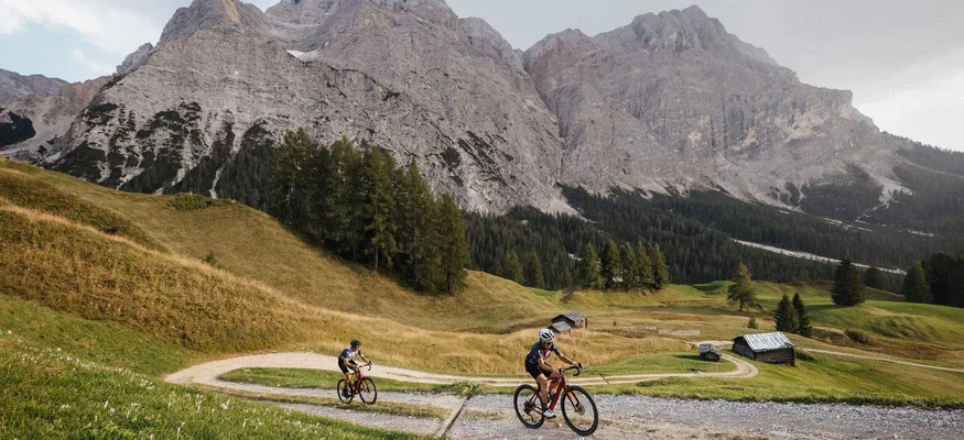 Zwei Radfahrer auf einem Bergweg mit Alpen im Hintergrund