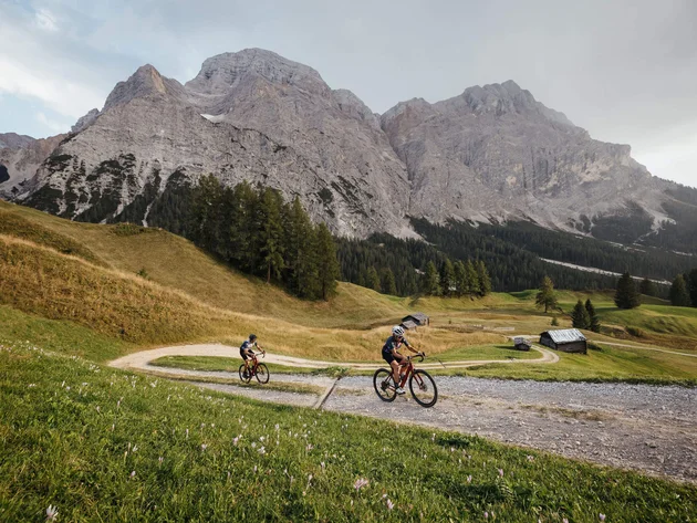 Zwei Radfahrer auf einem Bergweg mit Alpen im Hintergrund