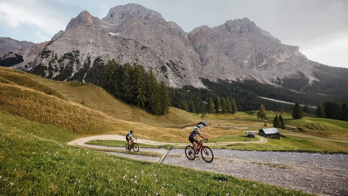 Zwei Radfahrer auf einem Bergweg mit Alpen im Hintergrund